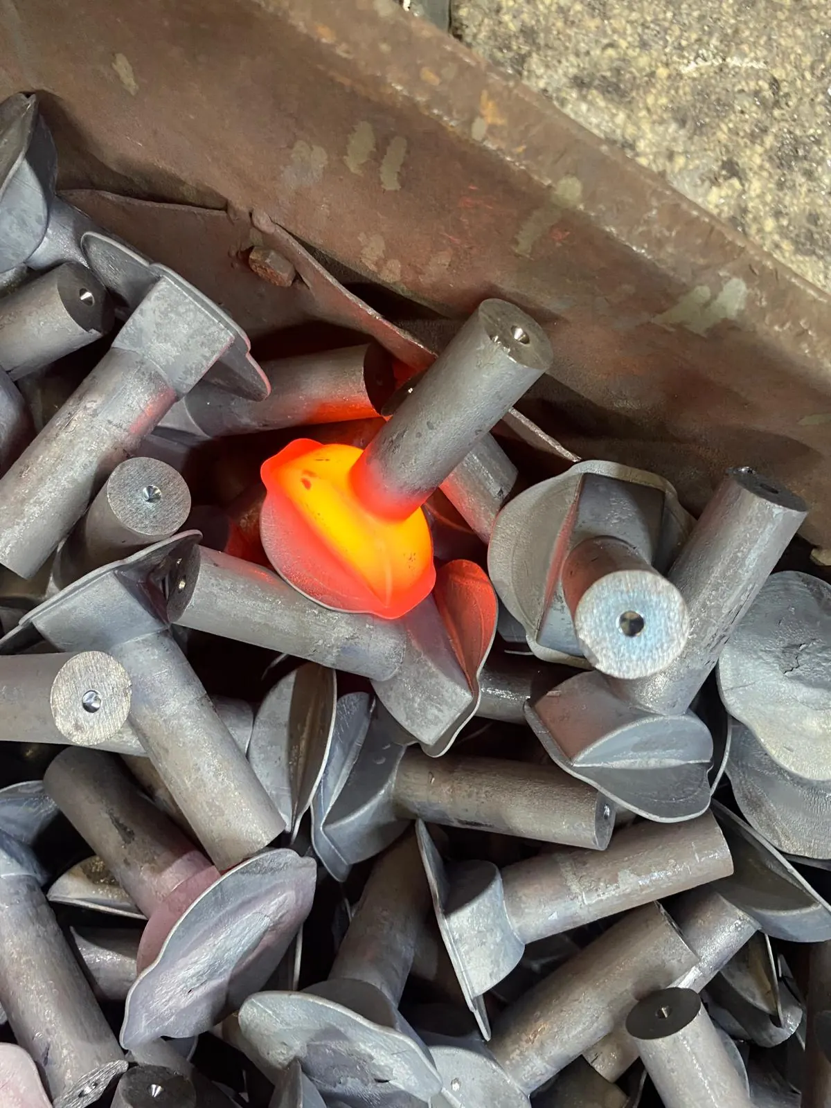 Factory photo showing forged parts with one glowing hot component